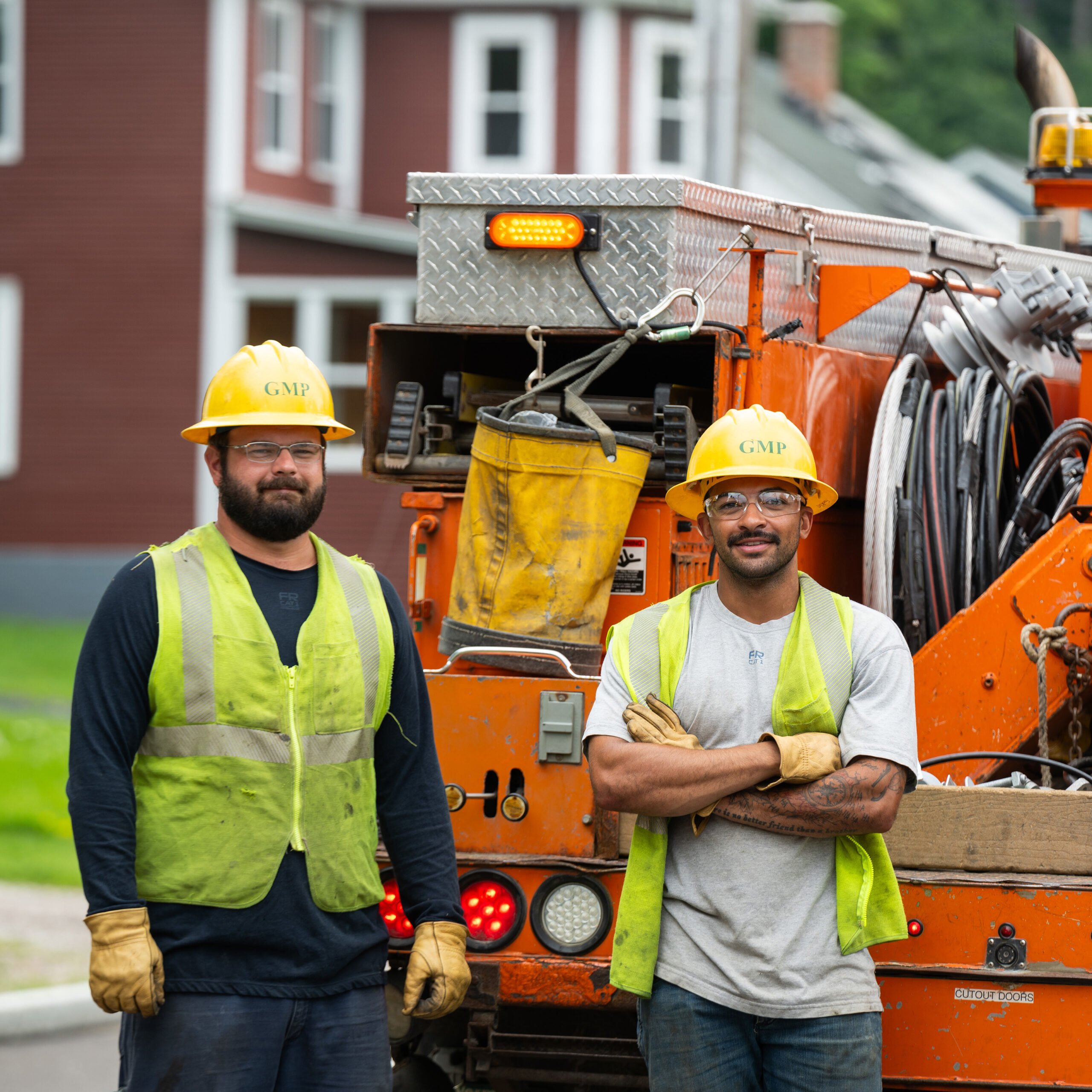 Two lineworkers standing next to a truck